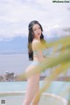 A woman in a blue bikini standing next to a pool.