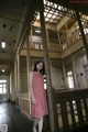 A woman in a red dress standing in an abandoned building.