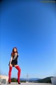 A woman in a black dress and red tights posing for a picture.