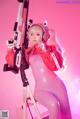 A woman in a pink outfit holding a gun.