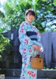 A woman in a blue and white kimono holding a basket.