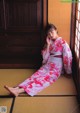 A woman in a pink kimono sitting on the floor.