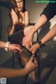 A woman is getting her feet spanked by two men.