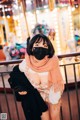 A woman wearing a face mask standing in front of a carousel.