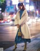 A woman in a white coat is walking down the street.