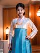 A woman in a blue and white hanbok poses for a picture.