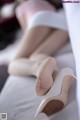 A woman laying on a bed with her feet up in high heels.