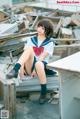 A woman in a school uniform sitting on a pile of rubble.