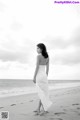 A woman in a white dress standing on a beach.